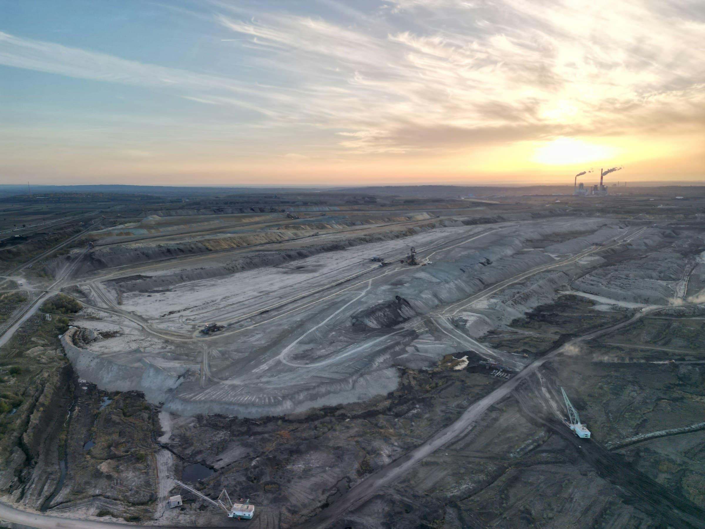 Aerial view of a large facility construction site with heavy equipment and earthwork at golden hour